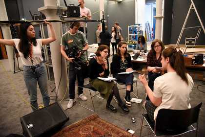 Four people sit and talk while being recorded by a camera and microphone