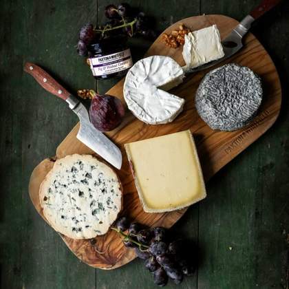 A wooden cheeseboard with a selection of cheeses and a knife