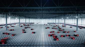 Large industrial building with gridded floor. Large boxes are placed across the floor with numbers on them.