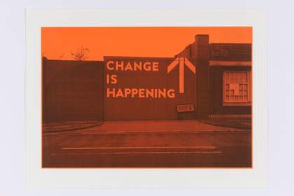 An orange-hued image of the words 'CHANGE IS HAPPENING' printed on a corrugated metal wall.