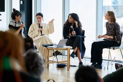 Four people sitting in chairs and speaking in microphones.
