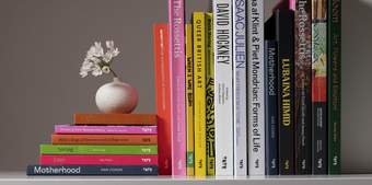 A selection of books with a white flower in a small rounded white vase