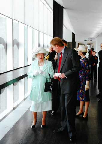 Her Majesty The Queen walking through a modern building.