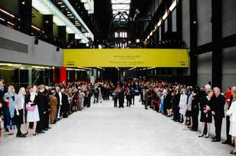 A crowd of people, including Her Majesty the Queen, inside the Turbine Hall at Tate Modern's opening.