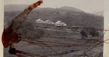 A black and white photograph of a landscape with houses built above the ground on stilts.
