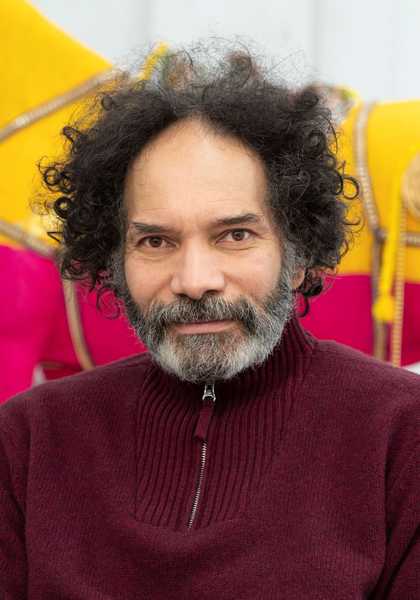 Portrait of a man from the shoulders up against a colourful background.