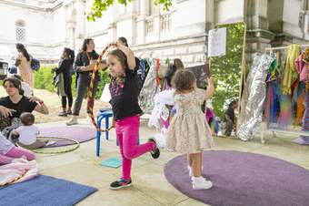 Children play with ribbons and costumes outside Tate Britain