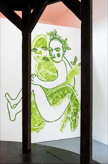Two green figures intertwined, drawn on a white wall
