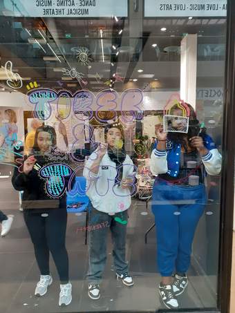 Three young people drawing on glass to promote their exhibition