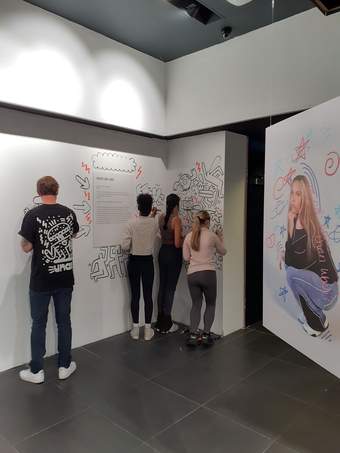 Photograph of young people decorating the walls in an art space