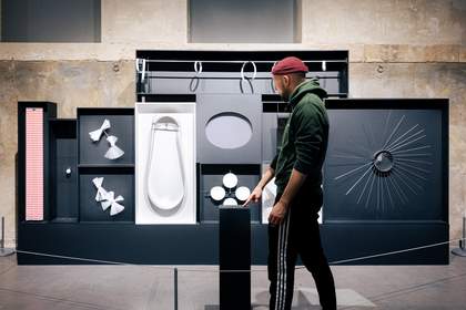A man stands in front of a wall of open cases, each with a different Julio le Parc artwork within them, which move when you press a button