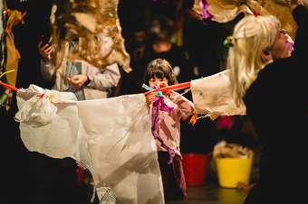 a girl affixes fabric to a washing line in an art studio