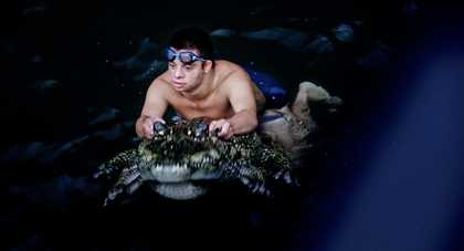 a person wearing goggles swims underwater with lots of fish around them