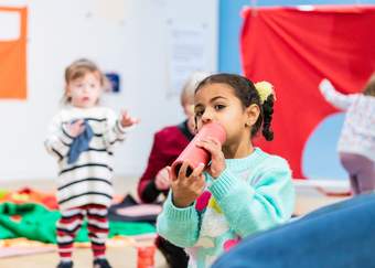 A girl blows through a cardboard tube in a families workshop