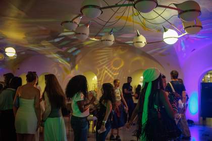 Image of a group of people dancing in the cafe with colourful lights reflecting