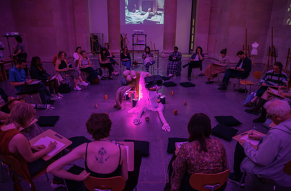 Life drawing workshop with people sitting in a circle around sculpture.