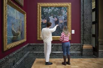 A man and a woman looking at painting of two children holding lanterns