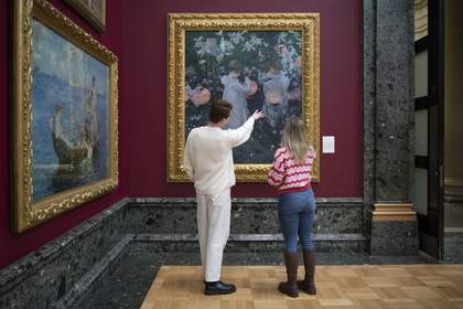 A man and a woman looking at painting of two children holding lanterns