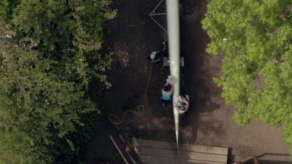 People canoeing on a river with greenery on each side of the water.