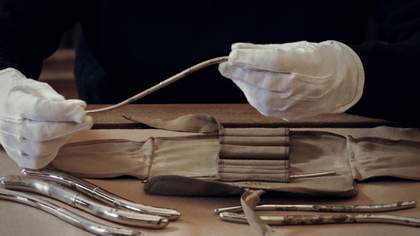 Gloved hands holding a medical instrument.