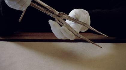 Gloved hands are handling a medical instrument.