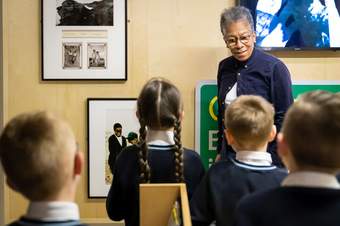 A photograph of artist Ingrid Pollard talking to a small group of school children on Mobile Museum