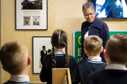 A photograph of artist Ingrid Pollard talking to a small group of school children on Mobile Museum