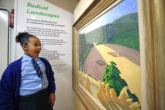 A photograph of a child in school uniform looking happily at an artwork on the Mobile Museum
