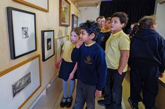 A small group of children looking intently at an artwork on the Mobile Museum