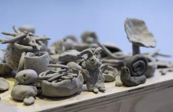 Handmade clay objects including animals and natural forms placed on a shelf