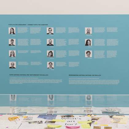 A museum interpretation display on a wall listing the names and images of the curators of the exhibition.