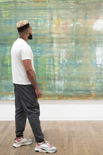 A person looking at a large green abstract painting