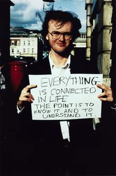 Man holding a placard reading 'Everything is connected in life, the point is to know it and to understand it'