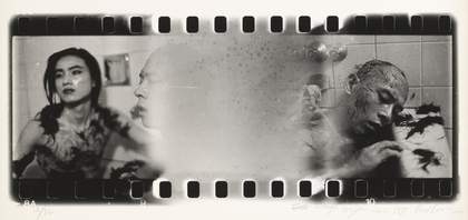 black and white image of negetive film still showing two people in a bathroom with off cuts of hair on their bodies and head