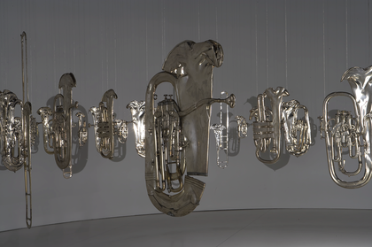 Squashed brass band musical instruments hung from the ceiling in a circle