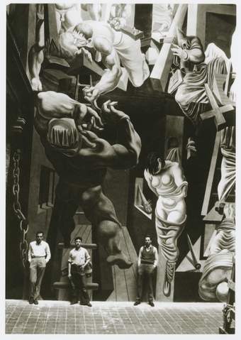 Black and White image of two men, Philip Guston Reuben Kadish and Jules Langsner standing in front of a large mural.