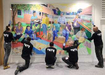 Tate staff in black Tate t-shirts holding a large painting