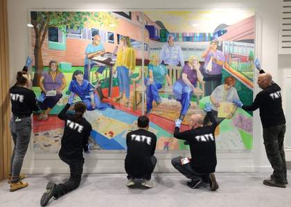 Tate staff in black Tate t-shirts holding a large painting