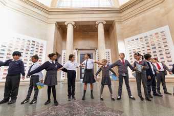 Young people gathered at Tate Britain, standing side-by-side with their arms outstretched.