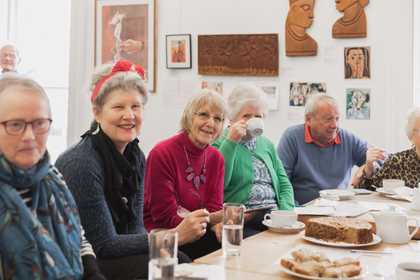 women around a table. smiling and looking at the camera.