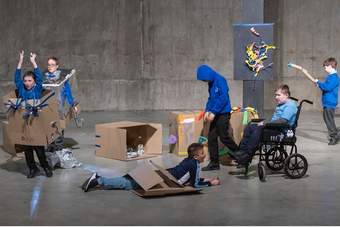 A group of young people play with decorated cardboard boxes