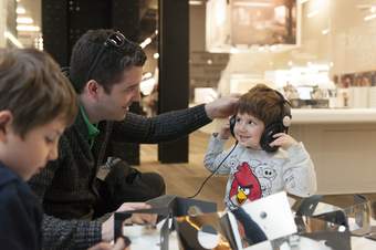 A boy with headphones on smiles at his father