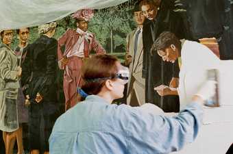 Rosie Hastings, wearing goggles, applies plaster to a partially painted fresco