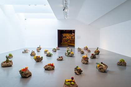 A selection of large rocks covered in fruit and vegetables in a large white room.