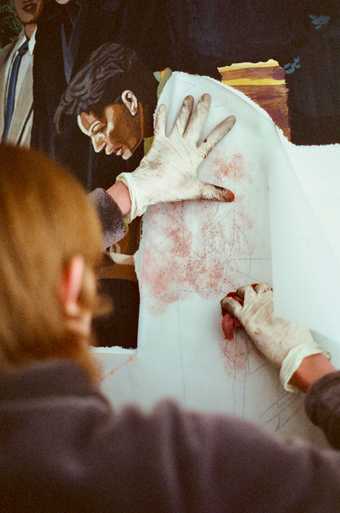 Hannah Quinlan applies pigment to a cartoon using a cloth
