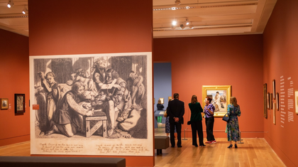 An art gallery exhibition with people discussing a painting