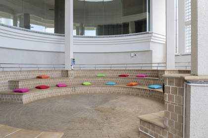 The large, curved brick seating area at the entrance of Tate St Ives, with lots of colourful cushions dotted around for people to sit on.