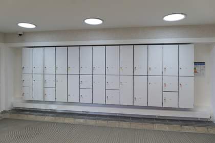 A long wall with two rows of tall white lockers.