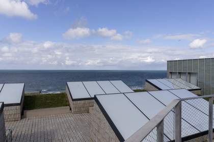 The roof of Tate St Ives, largely covered with large grey solar panels. It overlooks the sea.