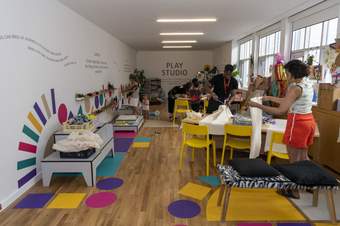 People doing activities in a colourful room with playful writing and shapes on the walls